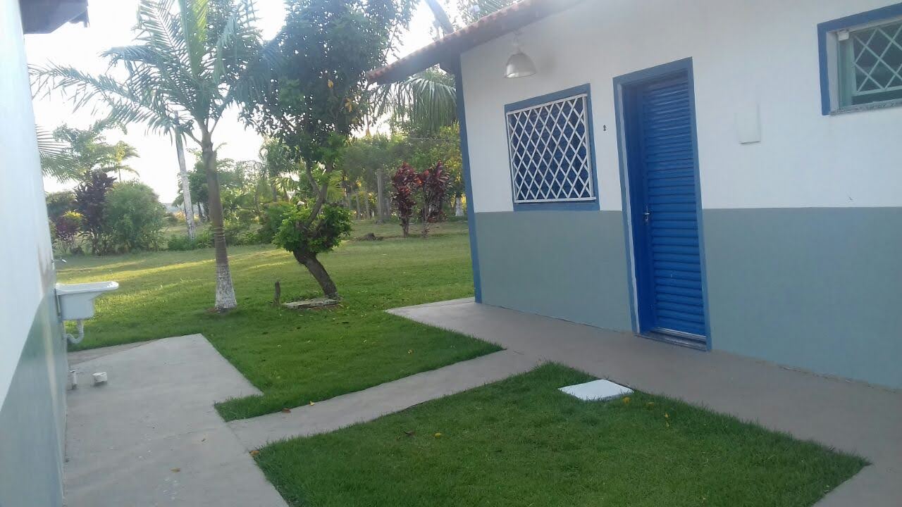 Entrada de acomodação com porta azul e jardim ao redor