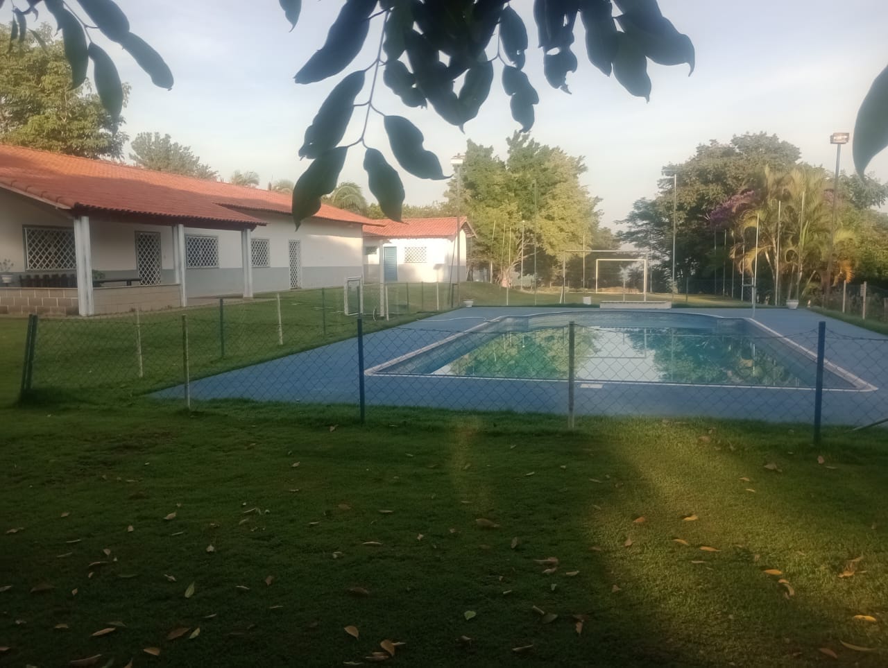 Piscina do Espaço Campestre Wannel ao lado do salão, com campo ao fundo